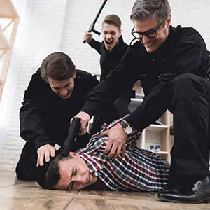 Three men restraining a man on the floor - Darryl A. Stallworth Law Office